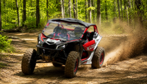 2026 Can-Am Maverick X3 X DS Turbo RR with Smart-Shox driving through a wooded off-road trail and kicking up dust