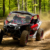 2026 Can-Am Maverick X3 X DS Turbo RR with Smart-Shox driving through a wooded off-road trail and kicking up dust